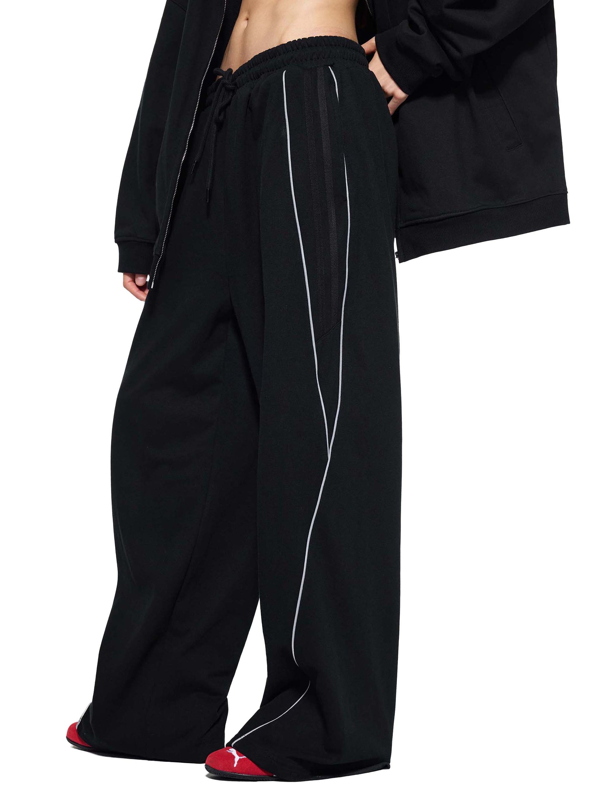 Side view of black Genzerz pants with white piping, styled for streetwear aesthetic.