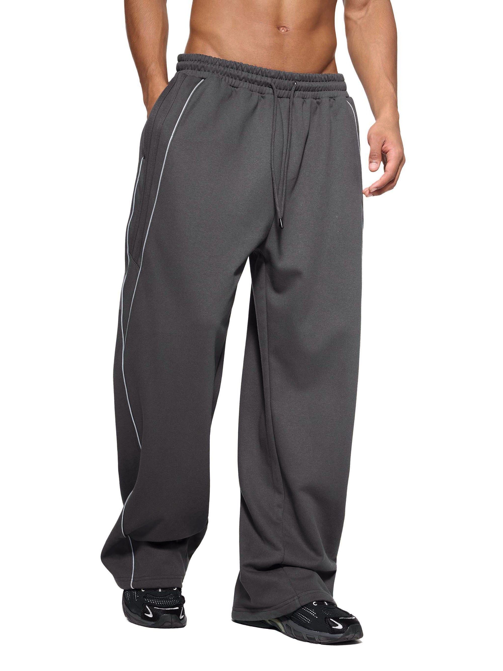 Model wearing gray Genzerz track pants with drawstring waist and white side stripes.