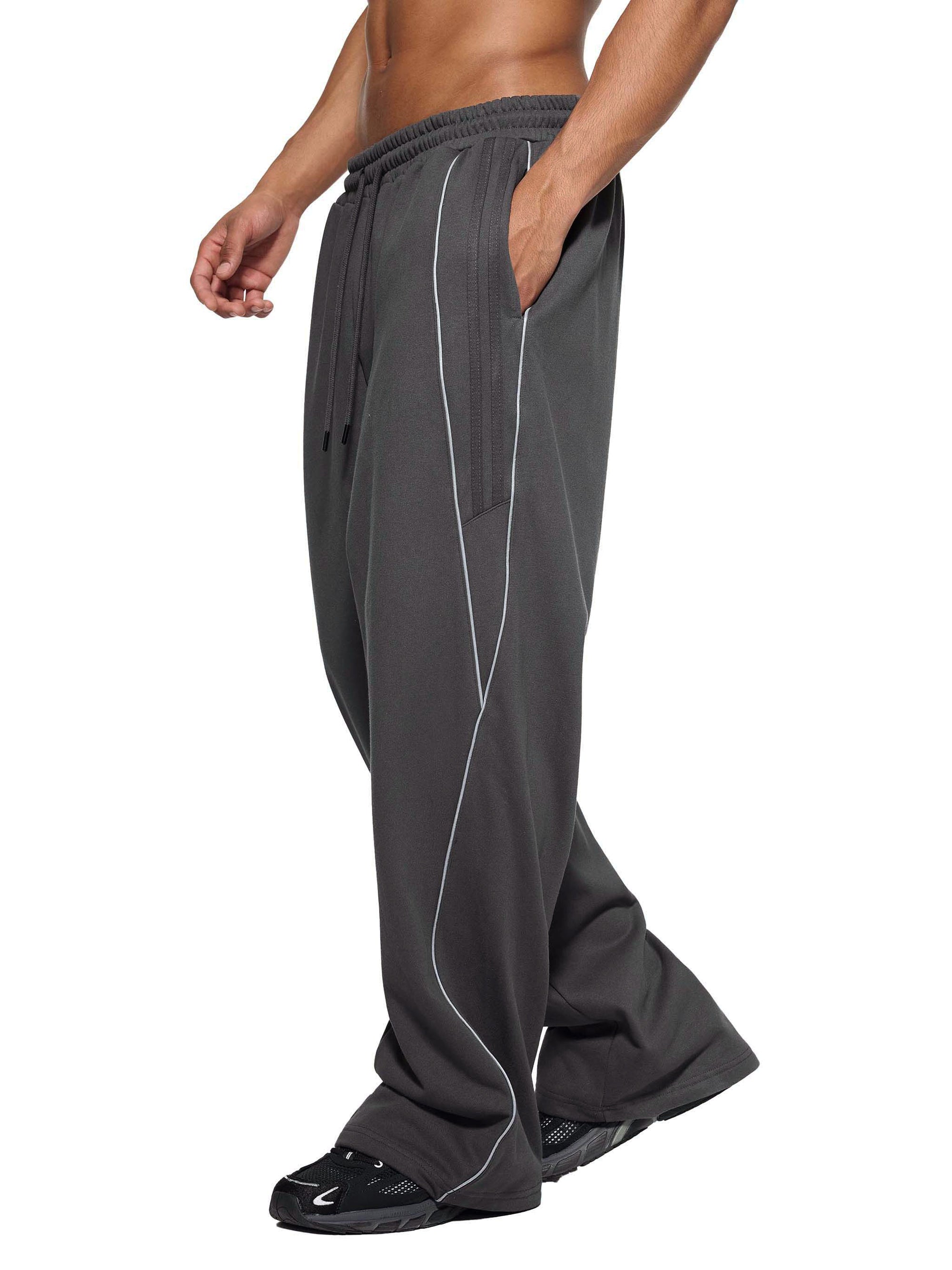 Side view of gray Genzerz sweatpants with white piping and relaxed streetwear fit.